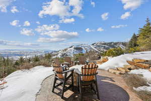 Snow covered patio with a mountain view and a patio