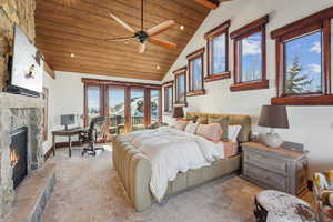 Bedroom with a stone fireplace, lofted ceiling with beams, access to exterior, recessed lighting, and a desk