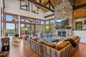 Living area featuring a fireplace, a high wooden beamed ceiling, and wood-type flooring