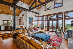 Living room with hardwood / wood-style floors, a high wooden beamed ceiling, and hanging lights