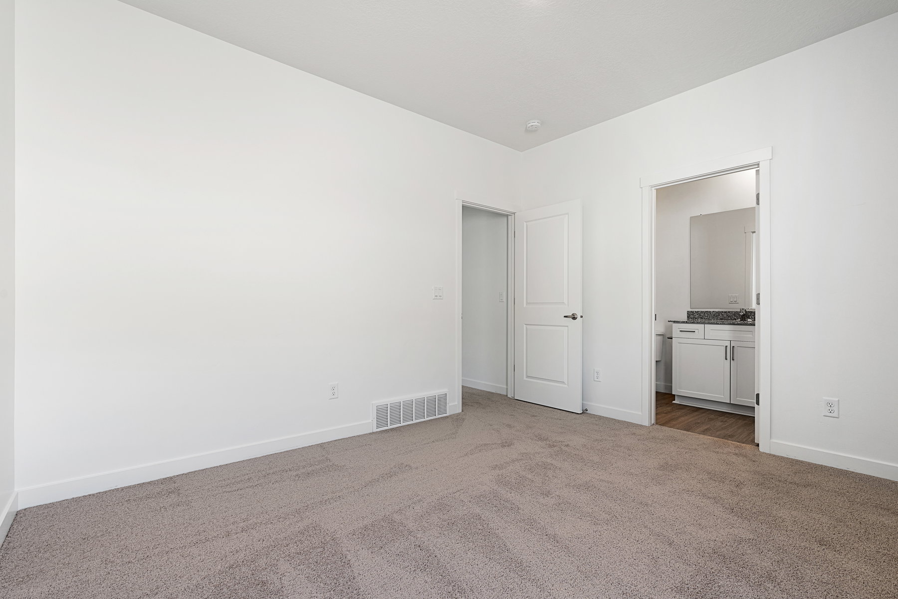 Unfurnished bedroom featuring dark carpet and connected bathroom