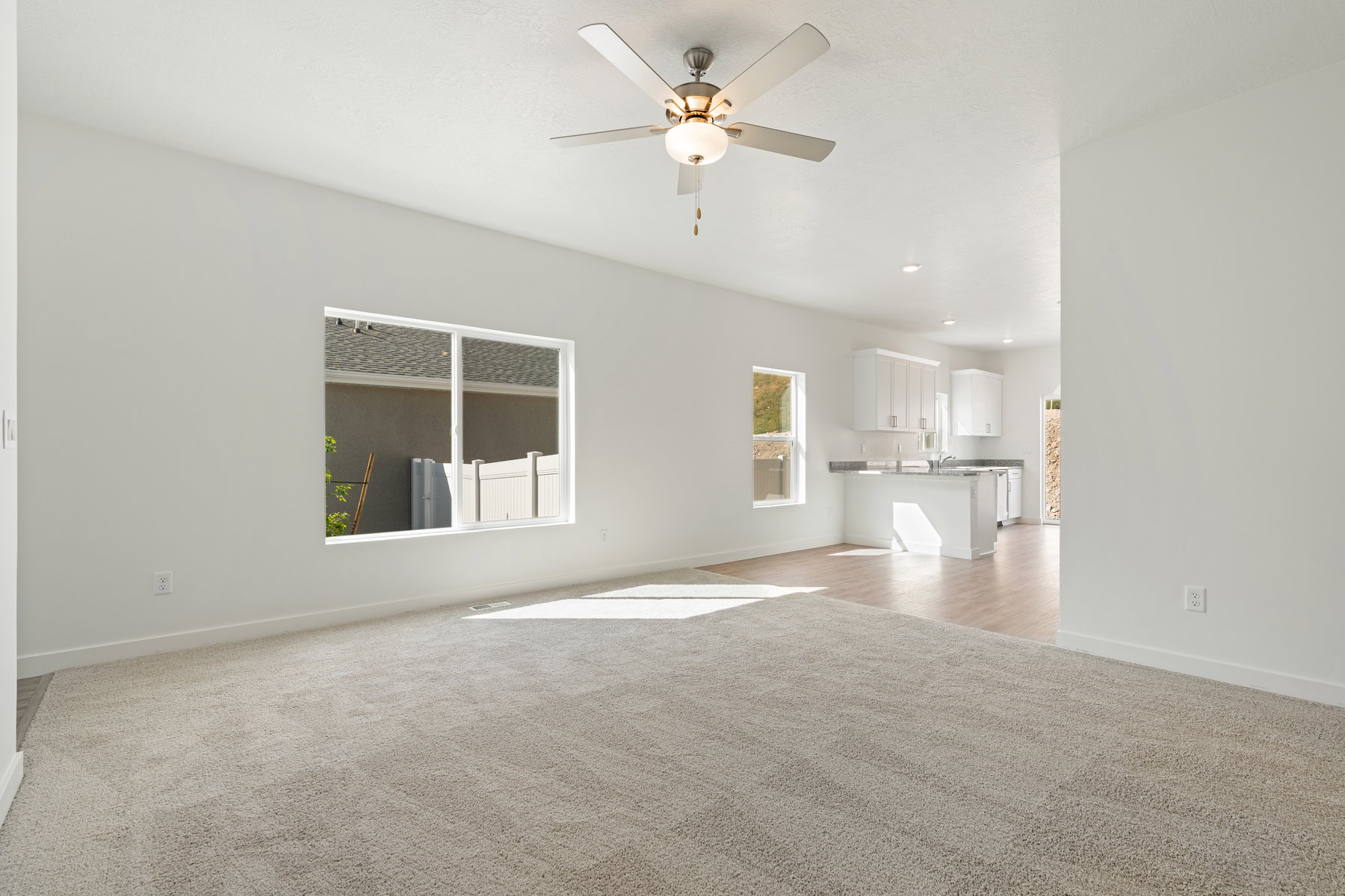Unfurnished living room with light colored carpet and ceiling fan