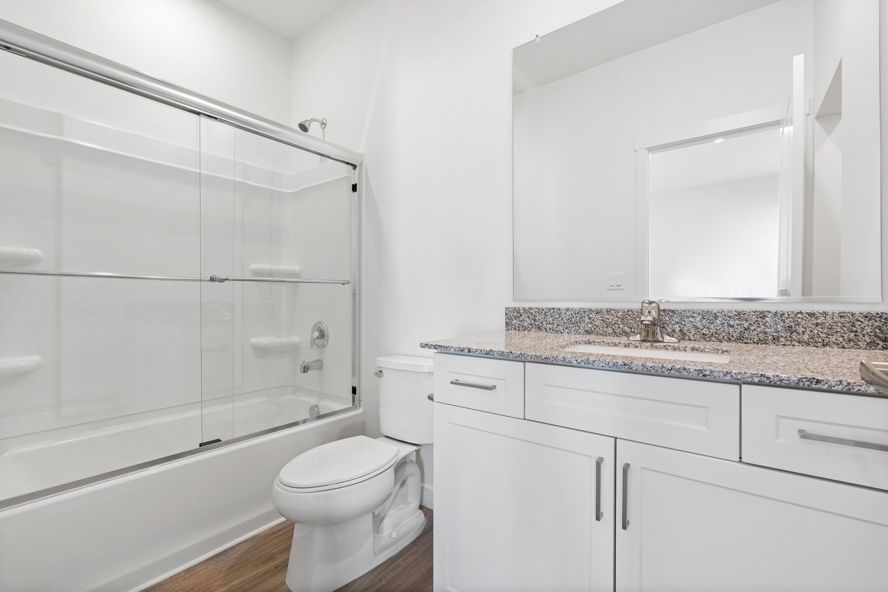 Full bath with vanity, dark wood-style flooring, and shower / bath combination with glass door