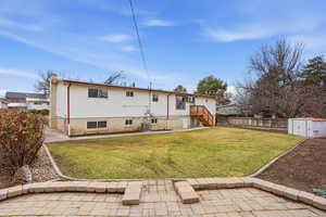 Rear view of house featuring a fenced backyard, a patio area, a gate, a shed, and brick siding