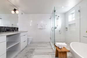 Bathroom featuring tile walls, vanity, a shower stall, and a freestanding bath