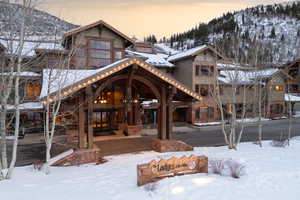 Snow covered property featuring stone siding and a mountain view