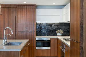 Kitchen featuring modern cabinets, stainless steel appliances, wood finish cabinetry, light stone counters, and recessed lighting