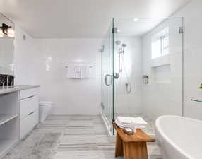 Bathroom with tile walls, a shower stall, vanity, and a freestanding bath