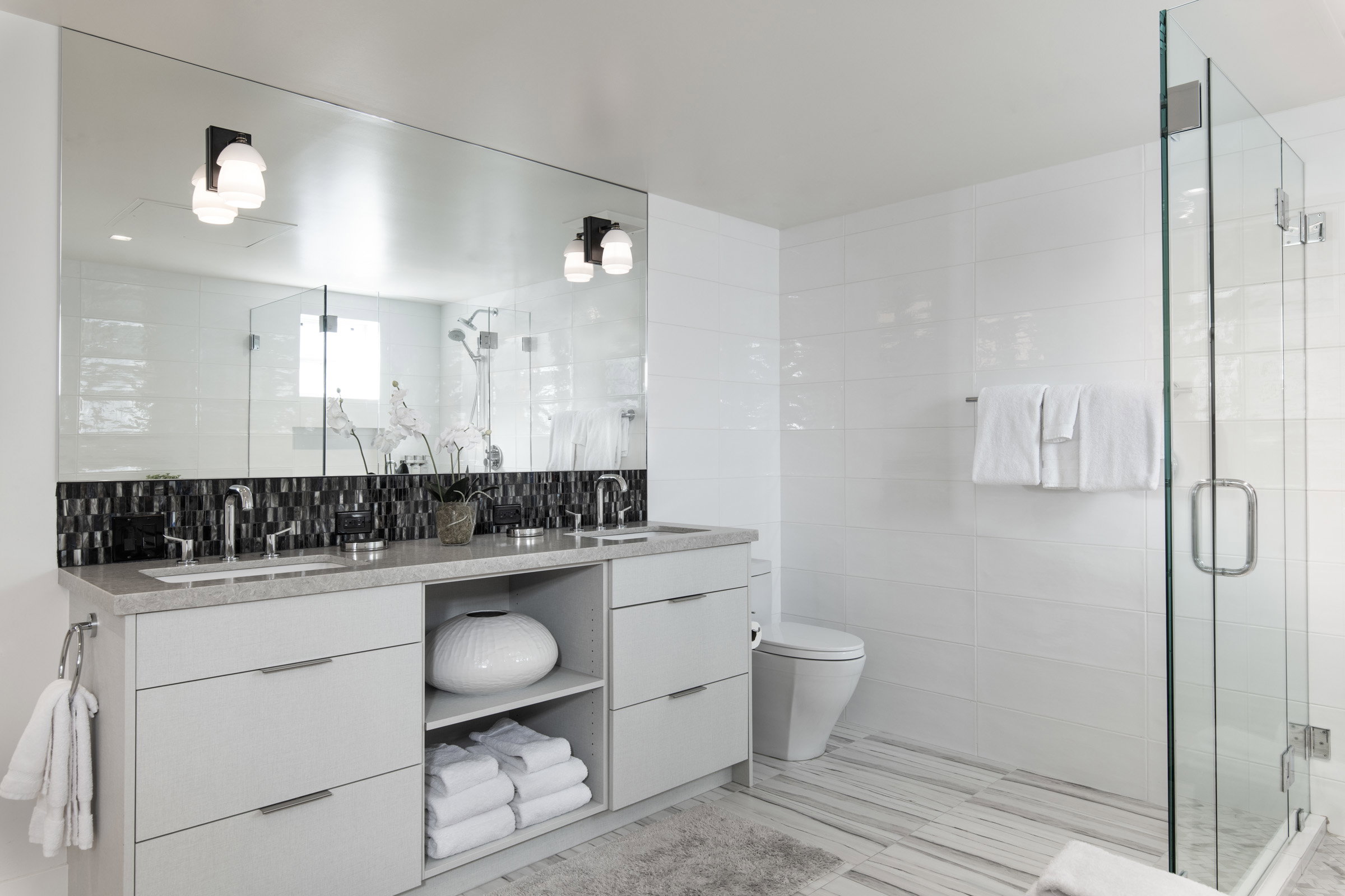 Bathroom with tile walls, double vanity, and a stall shower