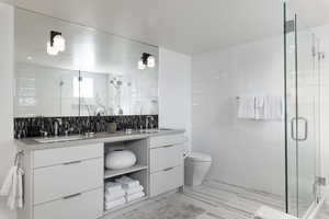 Bathroom with tile walls, double vanity, and a stall shower