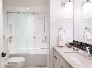 Bathroom featuring vanity, enclosed tub / shower combo, and tile walls