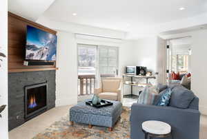Living area featuring carpet flooring, a stone fireplace, plenty of natural light, and recessed lighting