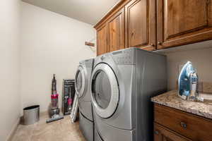 Laundry room with separate washer and dryer, light tile patterned floors, a textured ceiling, and cabinet space