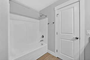 Master bathroom with light wood finished floors and bathing tub / shower combination