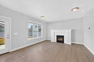 Unfurnished living room with light wood-type flooring and a glass covered fireplace