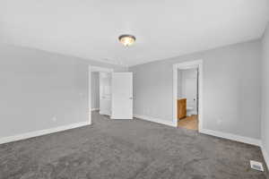 Master bedroom with light carpet and ensuite bathroom