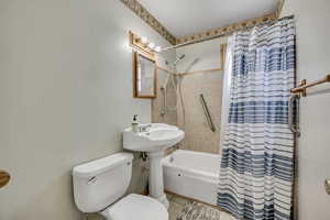 Bathroom with shower / bathtub combination with curtain and toilet