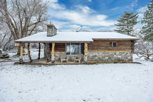 View of front facade with stone siding, a chimney, and a patio