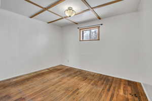 Empty room featuring wood-type flooring and coffered ceiling