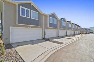 View of front of property featuring board and batten siding, a residential view, concrete driveway, and an attached garage