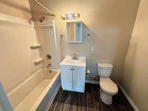 Bathroom featuring vanity, tub / shower combination, and dark wood-type flooring
