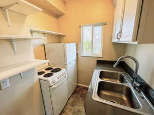 Kitchen featuring white electric range, white cabinets, open shelves, and dark countertops