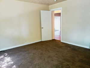 Unfurnished room with dark carpet and a textured ceiling