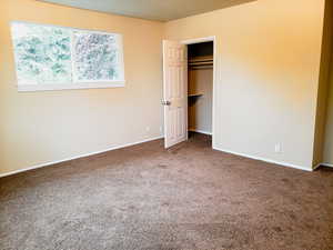 Unfurnished bedroom with carpet flooring and a walk in closet
