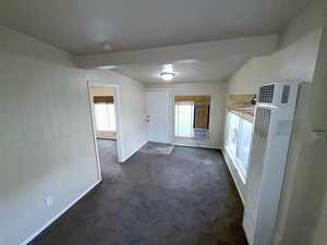 Unfurnished living room with a heating unit, dark carpet, and cooling unit