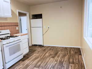 Kitchen with white appliances, white cabinetry, dark wood-style flooring, tile countertops, and decorative backsplash