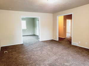 Spare room featuring dark carpet and a textured ceiling