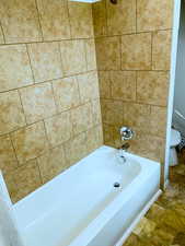 Full bath featuring shower / bath combination and stone finish floors
