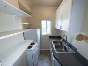 Kitchen featuring white range with electric cooktop, dark countertops, and white cabinetry
