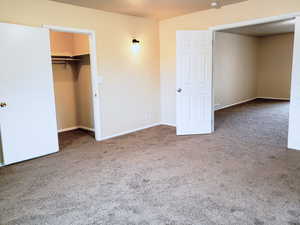 Unfurnished bedroom with light carpet and a walk in closet