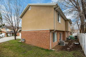 View of property exterior featuring brick siding, stucco siding, and a fenced backyard