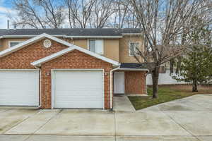 Traditional home featuring concrete driveway, brick siding, roof with shingles, and stucco siding