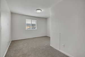 Empty room featuring light colored carpet and baseboards