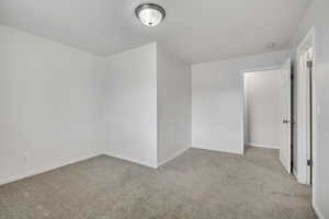 Unfurnished bedroom with light colored carpet and baseboards