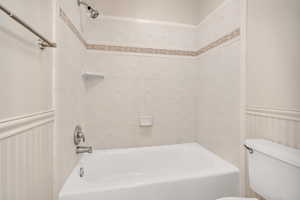 Full bathroom featuring a wainscoted wall and shower / tub combination
