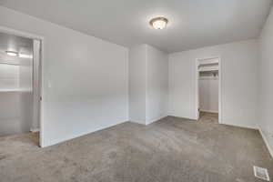 Unfurnished bedroom with a spacious closet and carpet floors