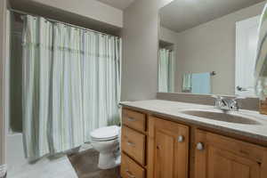 Full bathroom featuring vanity, shower / tub combo with curtain, and dark tile patterned floors
