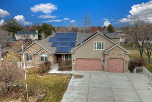 Traditional home featuring roof mounted solar panels, roof with shingles, brick siding, and concrete driveway