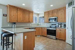 Kitchen featuring stainless steel appliances, a peninsula, recessed lighting, a breakfast bar area, and light countertops