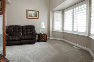 Living area featuring light colored carpet and baseboards