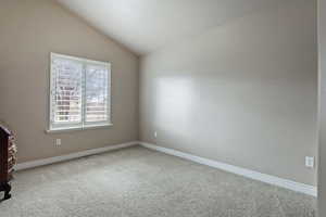 Spare room with light carpet and lofted ceiling