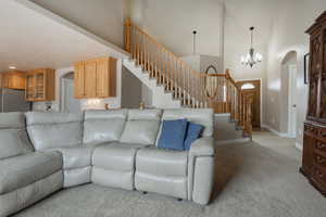 Living area featuring arched walkways, a high ceiling, light carpet, and a chandelier