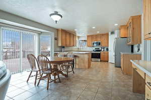 Kitchen with light countertops, stainless steel appliances, glass insert cabinets, recessed lighting, and a peninsula