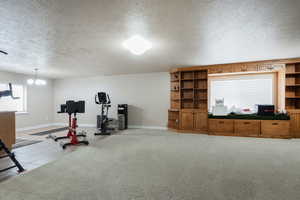 Workout area with a textured ceiling, light carpet, and hanging lights