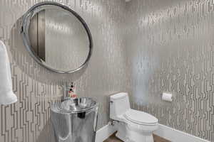 Bathroom featuring toilet and wallpapered walls