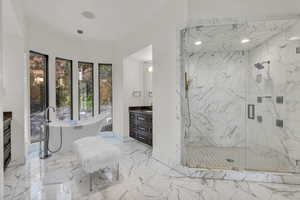 Bathroom featuring vanity, a marble finish shower, and a freestanding bath
